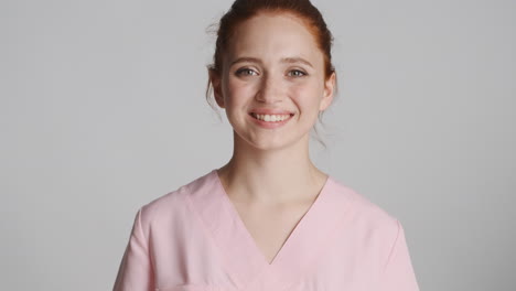 redheaded doctor in front of camera on gray background.