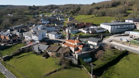 aerial orbit around lush green valley and historic church of san xoan de rio at midday