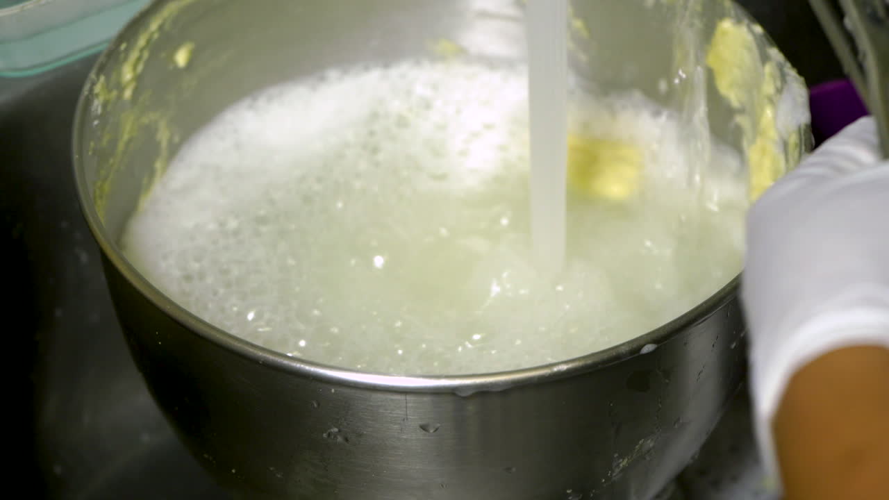 Lavare una ciotola sporca in un lavello da cucina sotto l'acqua corrente