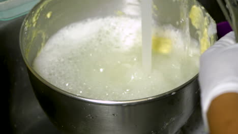 Washing-a-dirty-bowl-in-a-kitchen-sink-under-running-water