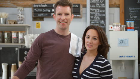 smiling business owners behind the counter of their cafe