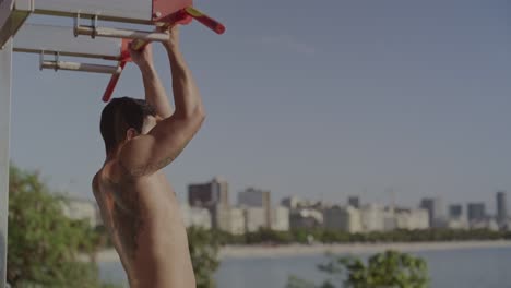 man doing pull-ups at an outdoor gym by the beach