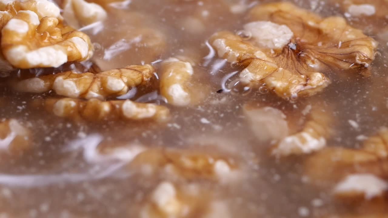 Raw Walnuts Soaking and Dropping into Water Close-Up