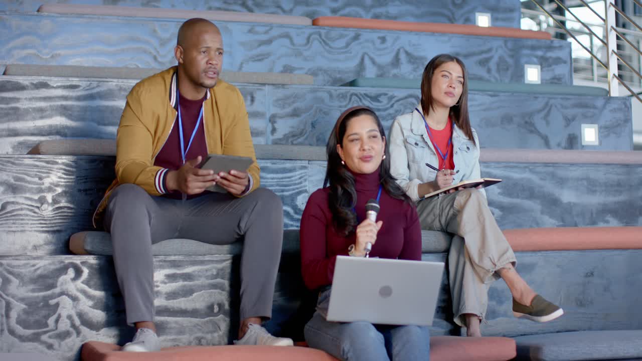 Reacting to speaker, diverse attendees tapping tablet, raising mic, writing notes at conference
