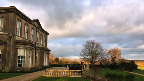 Vista-Lateral-De-La-Casa-Señorial-De-Grand-Leicestershire-Con-Nubes-Pasando-Y-Sobre-El-Patio-Y-Los-Jardines