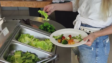 woman serving herself salad at a buffet