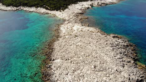 playa de alexia con aguas claras y costa rocosa en verano en grecia