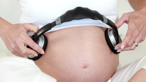 Mujer-Embarazada-Poniendo-Auriculares-Sobre-La-Protuberancia