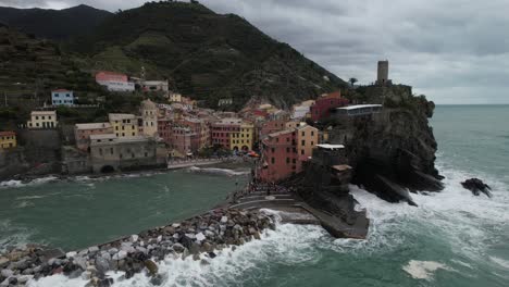 Drone-Orbital-Disparado-De-Izquierda-A-Derecha-Del-Pueblo-Italiano-De-Cinque-Terre-Junto-A-Las-Olas-De-La-Playa-Rompiendo-En-ángulo-Bajo