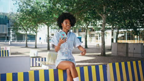 mujer joven usando teléfono inteligente en el parque de la ciudad