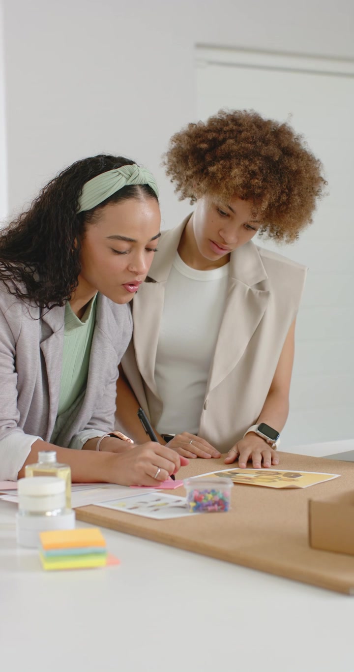 Video verticale: Donne afroamericane che indicano e poi scrivono post-it al tavolo, pianificando il layout