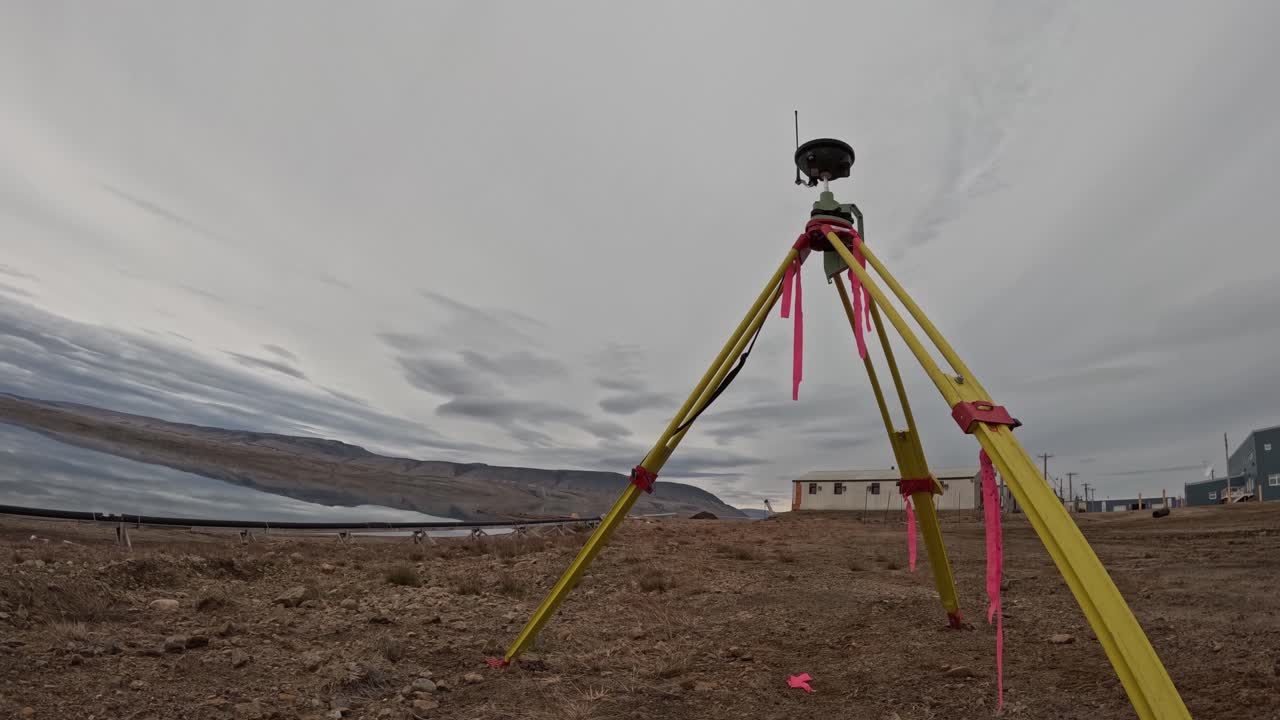 Timelapse af en GNSS-landmålingsbasestation i Eureka, Nunavut, Canada. Ishavet, rullende skyer, gold tundra, forskningsbygninger og fjerne bakker er synlige i det højarktiske miljø