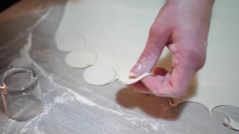 woman is putting circles of dough for cooking dumplings, hands closeup. process of cooking dumplings