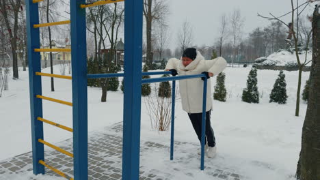 exercising on the horizontal bar on the sports ground. aged woman practicing sport in winter.