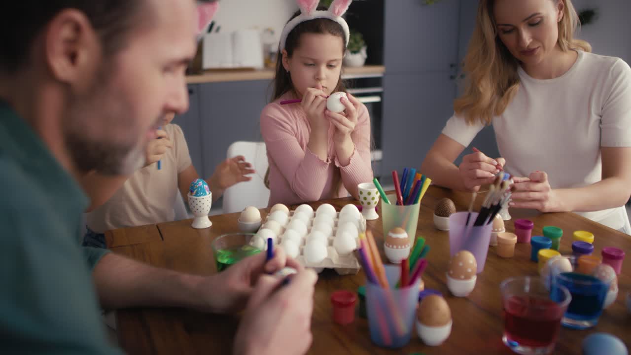 Caucasian family of four people decorating easter eggs at home.
