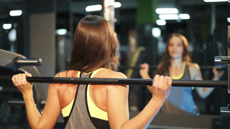 Fitness woman doing sit-ups with a barbell in the gym. Smith's machine in the gym. The ideal female figure. Fitness is the concept of a healthy lifestyle.