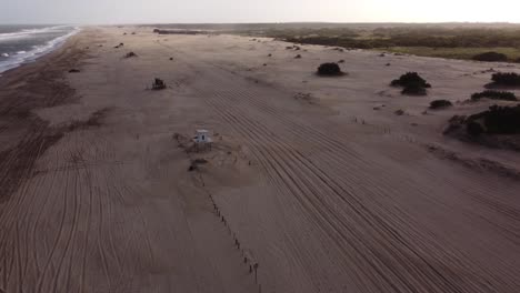 Time-lapse-shot-of-cars-driving-on-sandy-beach-during-sunny-day,-waves-in-motion-in-background