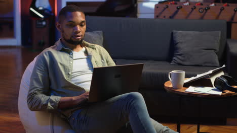 vertical video skilled african american man multitasking on laptop in cool living room