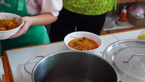 trabajadores tailandeses con cuencos de fideos khao soi