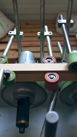 conveyor line with multiple rollers. timber bar is moved along the spinning shafts for following processing. vertical video