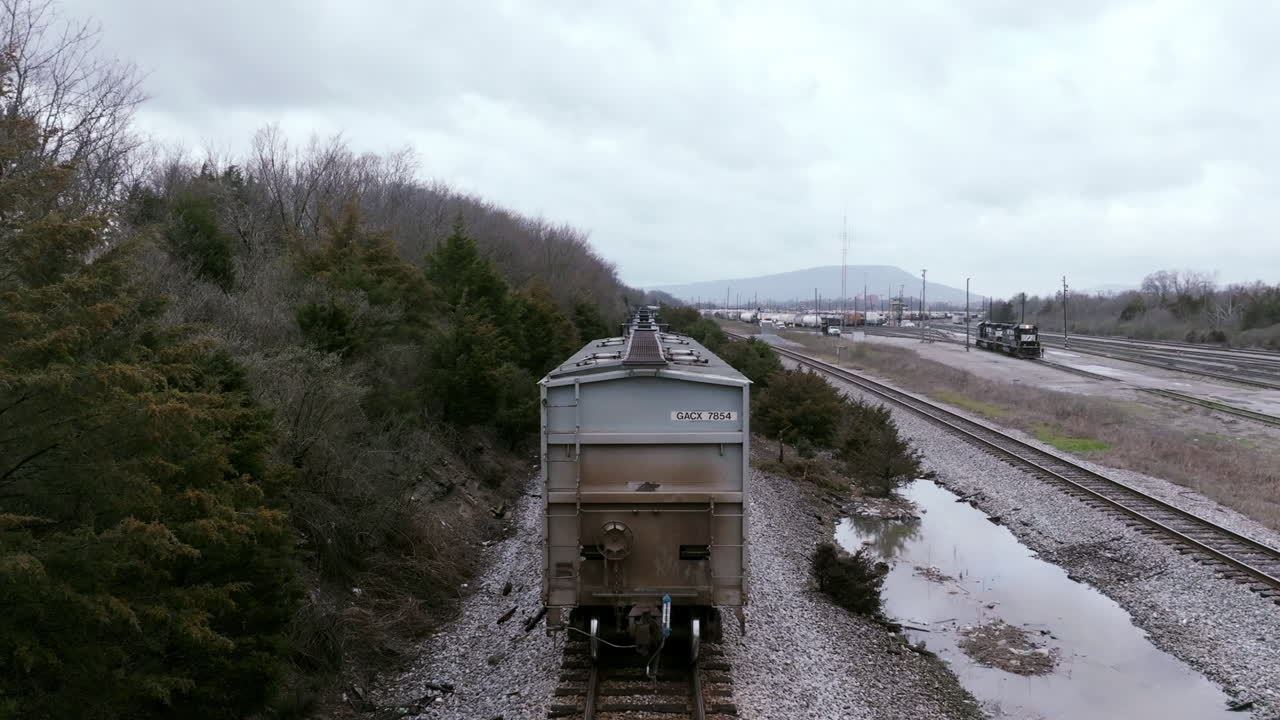 Aerial footage following the back of a train car moving along the tracks in the rail yard in Chattanooga, TN.