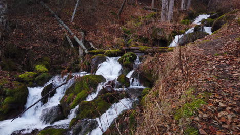 water fall on falls creek flowing over moss covered boulders and rocks in chugach state park near anchorage alaska in late autumn