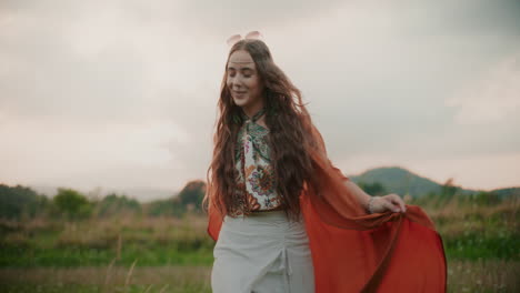 mujer feliz caminando contra un fondo de campos y puesta de sol