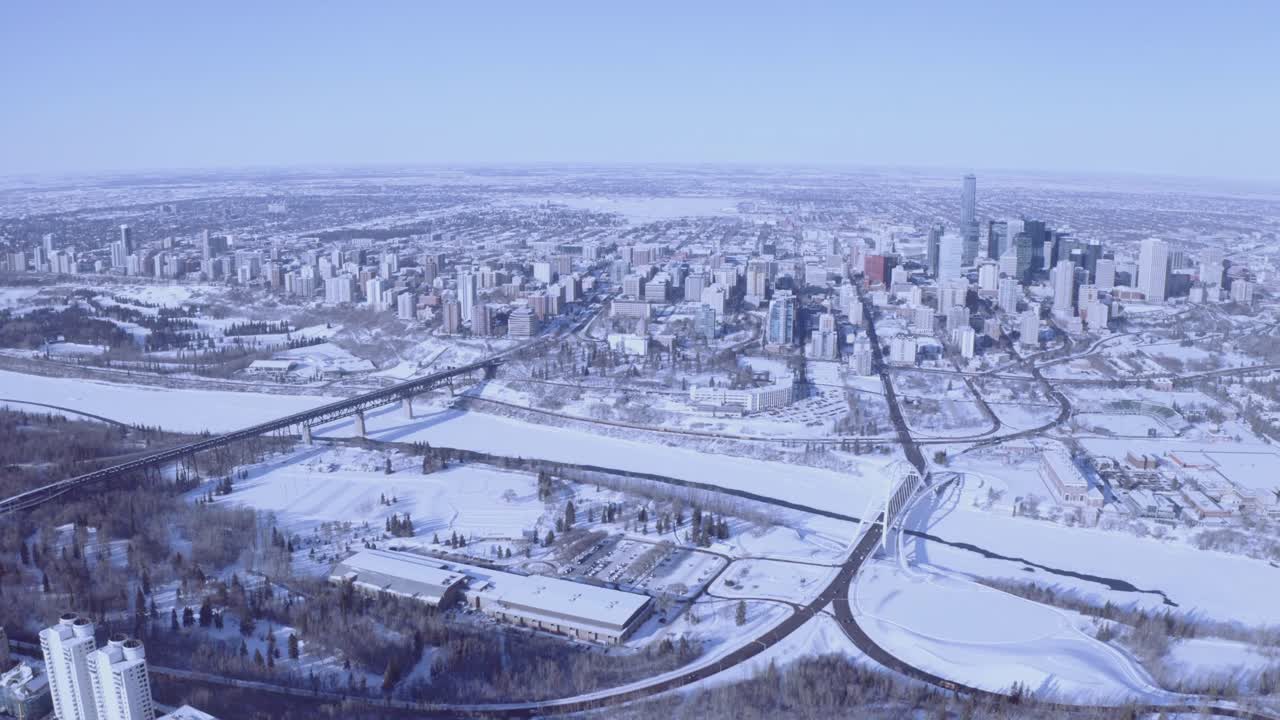panoramica aerea super alta fuori dall'inverno città innevata con sfumature blu cielo limpido di un orizzonte sinuoso con ponti che collegano al centro città attraversando fiumi ghiacciati innevati parchi foreste