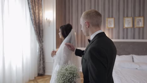 newlyweds young caucasian bride and groom first meeting at wedding day, making a kiss indoors