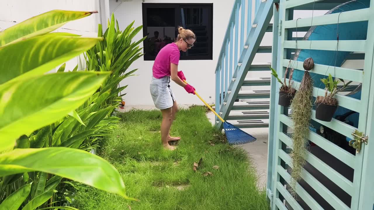 mujer rastrillando el césped en un patio trasero