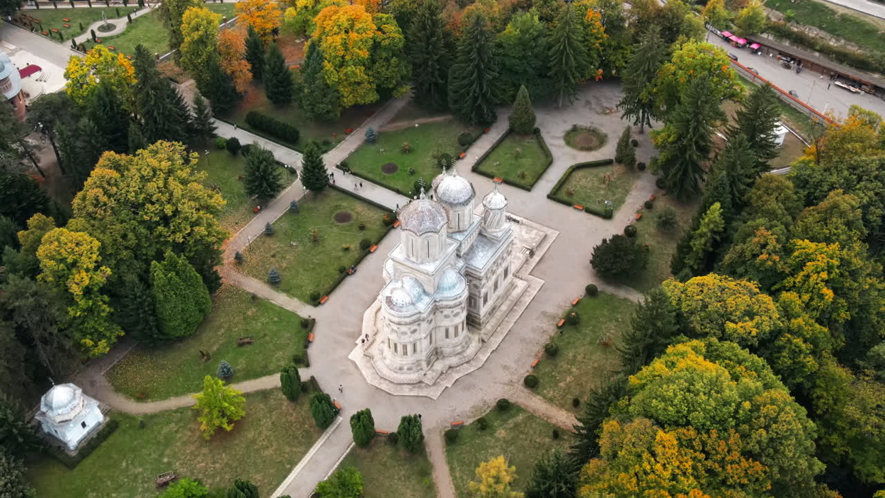 Aerial drone view of The Cathedral of Curtea de Arges, Romania. Square with greenery and people