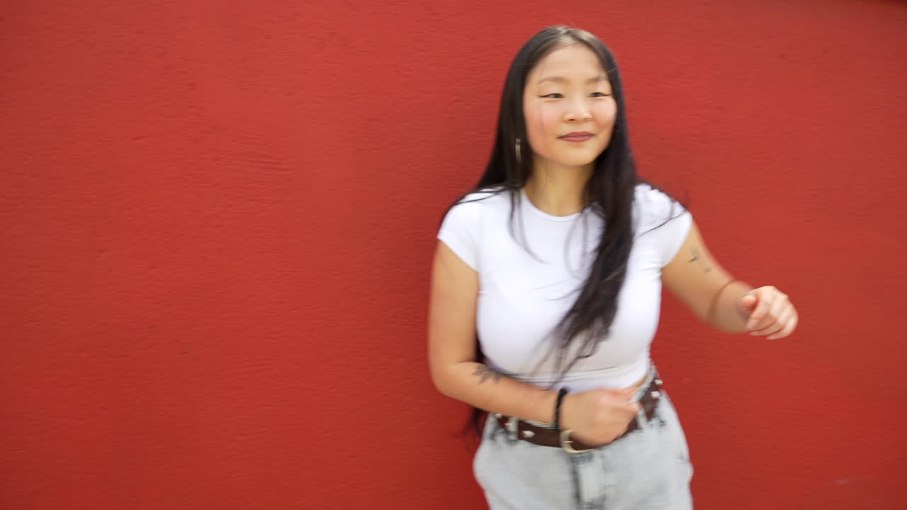 赤い背景の前で踊る女性。