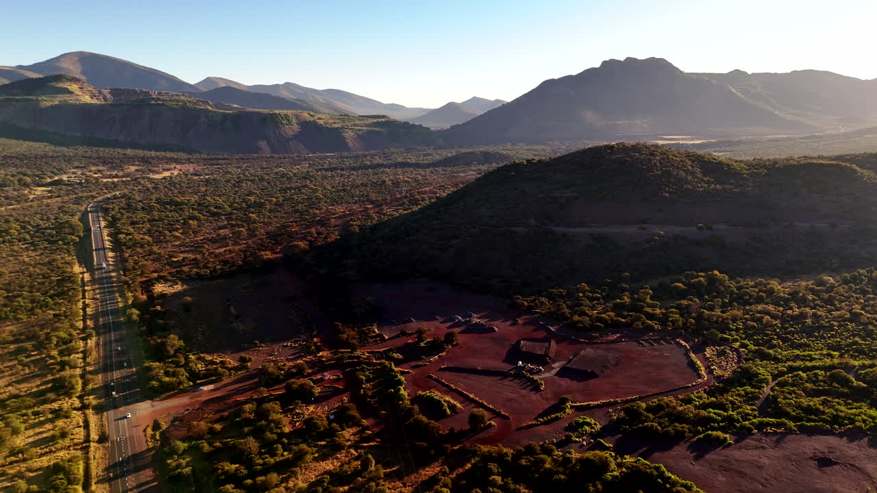 Red soil of open cast mine next to highway in remote countryside, aerial