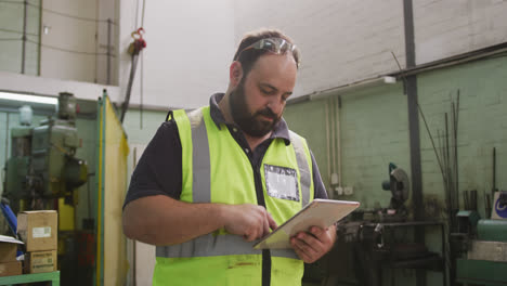 Caucasian-male-factory-worker-at-a-factory-wearing-a-high-vis-vest