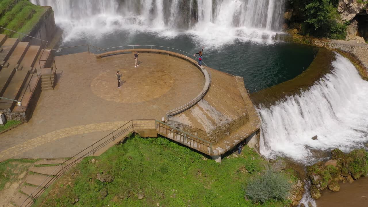 Jajce Waterfall in Bosnia and Herzegovina with tourist women taking pictures, Aerial hover shot