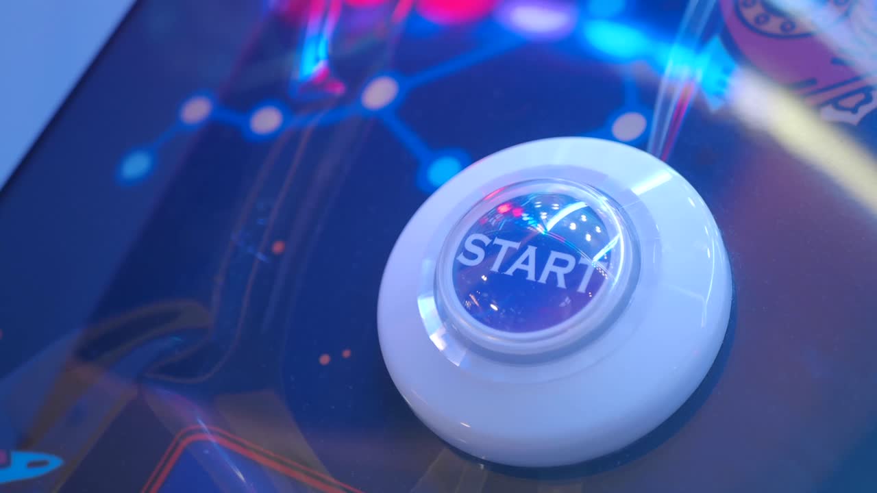 Person Pressing Start Button on Arcade Game