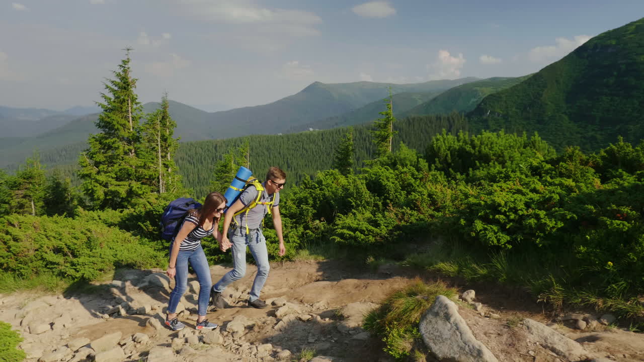 un chico ayuda a su novia a escalar un estilo de vida activo de montaña 4k video en cámara lenta
