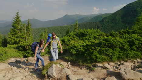 un chico ayuda a su novia a escalar un estilo de vida activo de montaña 4k video en cámara lenta