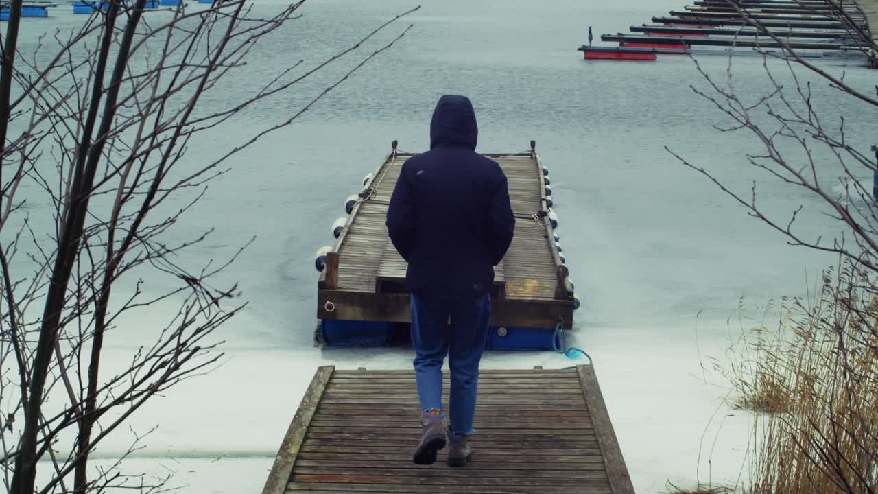 Uomo che cammina su un molo in un freddo paesaggio norvegese. Movimento lento.