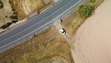 A-car-parked-near-a-road-in-campos-de-dos-torres,-cordoba,-spain,-aerial-view