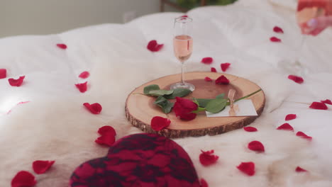 womans hand grabbing glass of sparkling rose wine in valentine's day setting