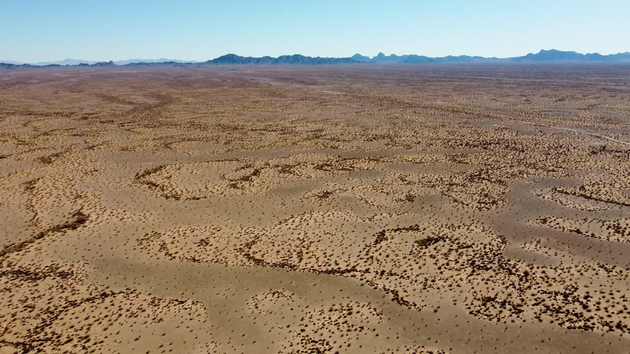 US, AZ, Quartzsite, Copperstone Mine, 2025-01-14 - Drone view flying over open desert with a dirt road on tte right