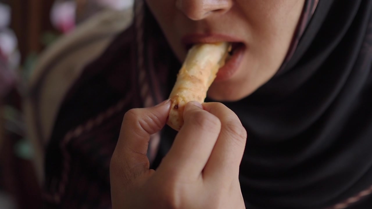 Woman in Hijab Eating a Crispy Spring Roll