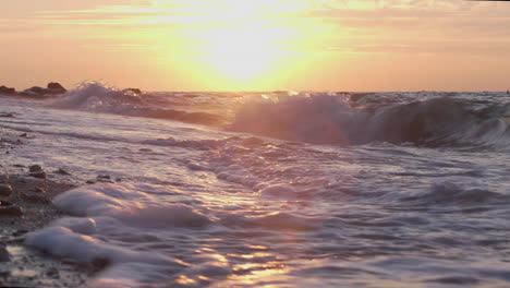 waves crashing on the beach at sunset