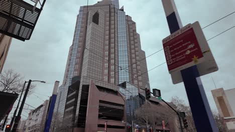 imágenes cinematográficas en movimiento de un alto edificio corporativo en sacramento, california con un cielo nublado gris en el fondo y cables de tren, graffiti y letreros en el primer plano en movimiento
