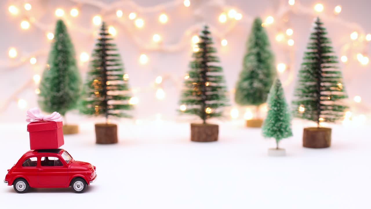 un coche vintage rojo conduciendo un regalo rojo para navidad en el techo.