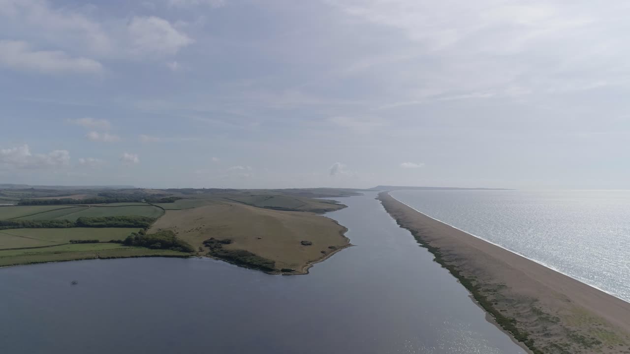 seguimiento aéreo mirando hacia el este a lo largo de la laguna de la flota y la playa de chesil en abbotsbury
