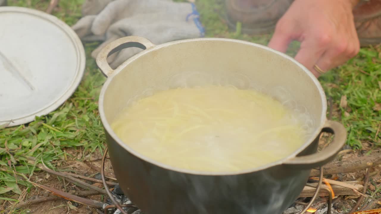 toma en ángulo alto de espagueti hirviendo en un recipiente de metal sobre una estufa con humo saliendo en loc binh, provincia de lạng sơn, vietnam durante el día