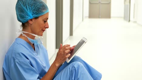 Surgeon-sitting-on-floor-and-using-digital-tablet