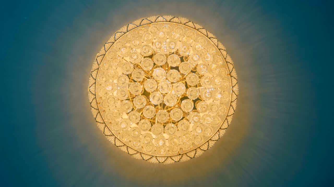 un hermoso candelabro redondo clásico con bolas de cristal colgando en el techo azul